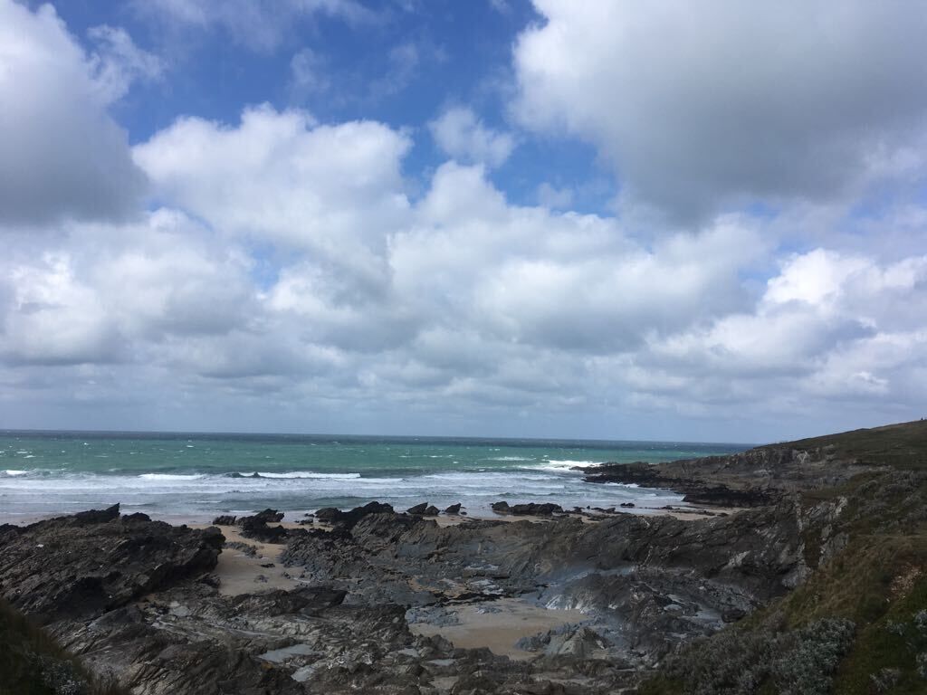 Un paysage côtier rocheux offrant une vue sur la mer et un ciel nuageux.