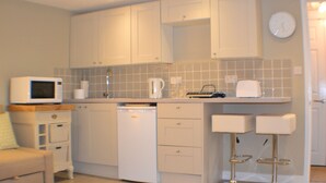 A compact kitchen with white cabinets, a microwave, a coffee maker, and a toaster.