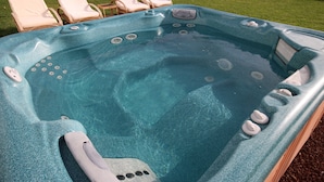 A hot tub with multiple jets, surrounded by lounge chairs on a grassy area. - Beautiful villa with garden, Jacuzzi and sea views (Arona)