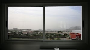 A view through a window with a view of a landscape including buildings, trees, and hills. - Beautiful villa with garden, Jacuzzi and sea views (Arona)