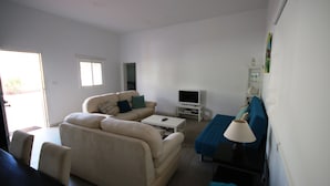 A living room with a beige sofa, a white coffee table, a TV on a stand, and a blue blanket on the floor. - Beautiful villa with garden, Jacuzzi and sea views (Arona)