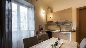 A compact kitchen with a gas stove, sink, and wooden cabinets. There is a dining table with a patterned tablecloth and potted plants. - Historic Center Salerno, ideal for getting around the city and the coast - Wi-Fi Free (Salerno)