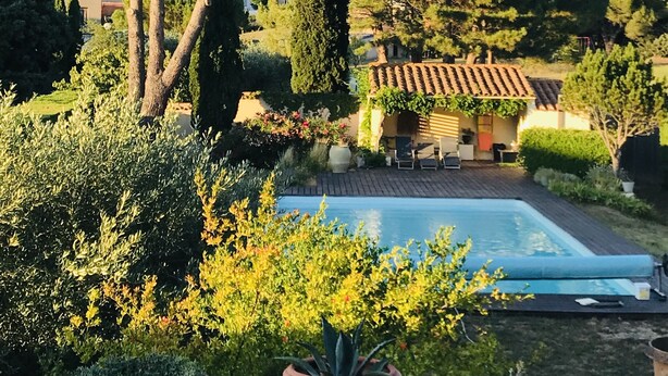 Zona junto a la piscina con suelo de baldosas, una pérgola y vistas a una colina.