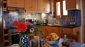 Une cuisine avec des meubles en bois, un dosseret carrelé, une cuisinière et un coin repas avec une table mise pour deux personnes.