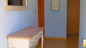 Un pasillo con un banco de madera, un espejo y una puerta.