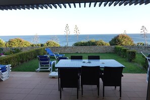 A patio with a table and chairs, overlooking a garden and the sea. - Beautiful Villa With Pool, Quiet Location Directly Overlooking The Sea (Praia da Luz)