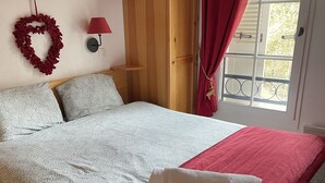 A bedroom with a bed, a wooden wardrobe, a window with curtains, and a wall decoration. - Winter/Summer holidays in St Gervais Le Bains Sleeps 4 (Saint-Gervais-Les-Bains)