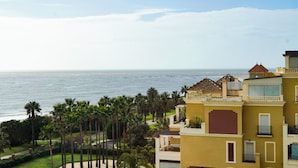 A coastal hotel with balconies, palm trees, and a view of the sea. - Luxury beach penthouse apartment in ISLA CANELA. The best views front line beach (URBANIZACION LOS CISNES)