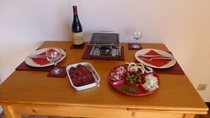 A wooden dining table set with plates, cutlery, a wine bottle, and a variety of food items. - Very well appointed Apartment in Chatel , very convenient for shops ,restaurants (Châtel)