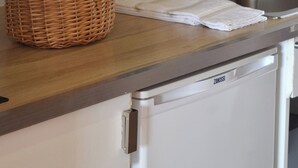 Una cocina con microondas, fregadero, lavavajillas y una cesta de verduras sobre la encimera.