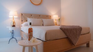 A neatly arranged bedroom with a bed, bedside lamps, a round mirror, and a small table with a glass and a flower.