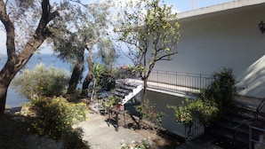 Ein Balkon mit Blick auf das Meer, umgeben von Grünpflanzen und einer Betonmauer.
