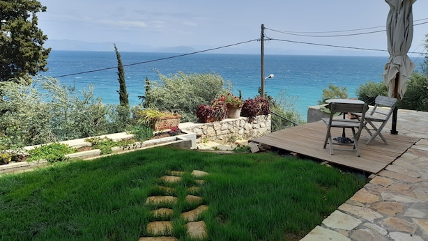 Eine Terrasse mit Meerblick, Steinstufen und Topfpflanzen.