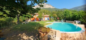 Zona residencial con piscina, una casa y montañas al fondo.