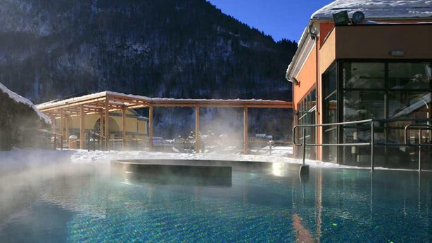 A clear pool with a wooden deck and glass enclosure, surrounded by a mountainous landscape. - Apartment/ flat - Cauterets (Cauterets)