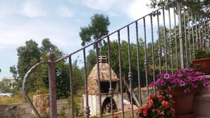 A stone structure with a chimney, surrounded by a metal fence and potted plants. - Peaceful Holiday Home. (Posada)