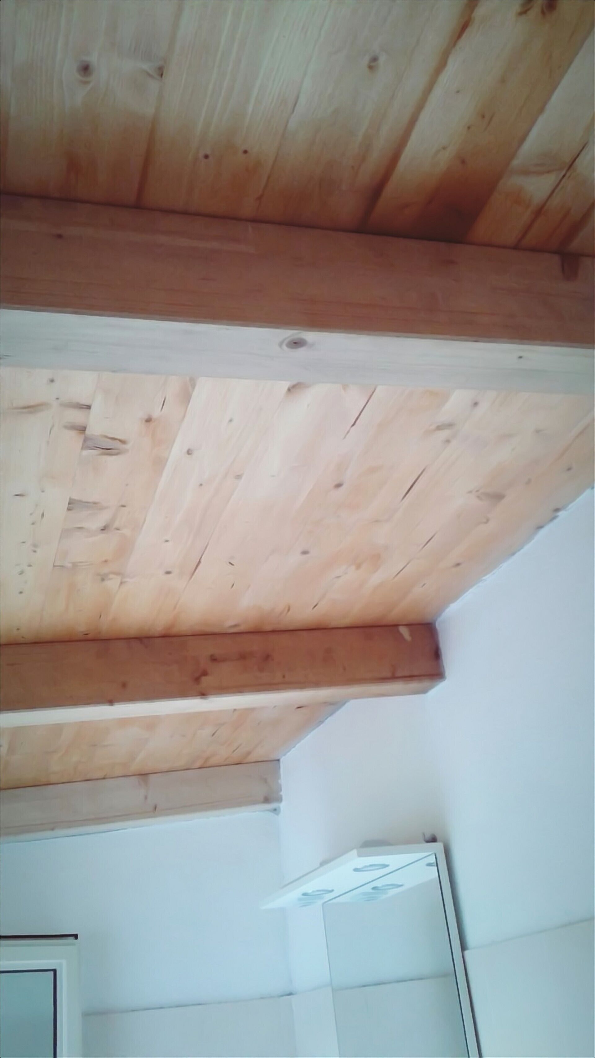 A room with a sloped ceiling supported by wooden beams.