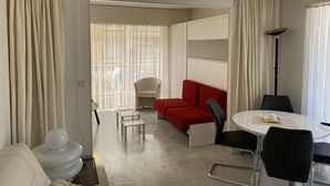 Une chambre d’hôtel moderne avec un canapé rouge, une table à manger blanche et une petite table blanche.