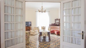 An open door leading to a dining area with a patterned floor, a chandelier, and a television in the background. - ** FAMILY APARTMENT IN TRASTEVERE ** 220sqm -6 bedrooms in the center of ROME!!! (Roma)