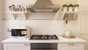 A kitchen with white cabinets, a microwave, a gas stove, and a kettle. - ** FAMILY APARTMENT IN TRASTEVERE ** 220sqm -6 bedrooms in the center of ROME!!! (Roma)