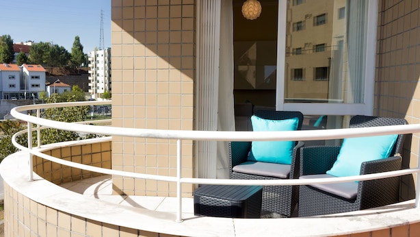 Ein Balkon mit Korbmöbeln und einem weißen Geländer.
