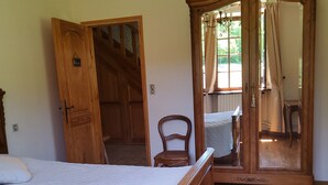 A bedroom with a wooden bed, a wooden wardrobe, a wooden chair, and a large mirror. - mansion - Fournels (Fournels)