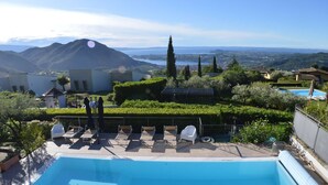 Una piscina con sillas de descanso, vistas a una montaña y un jardín bien cuidado.