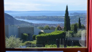 Vista desde una ventana que da a un paisaje costero con colinas, una masa de agua y una ciudad a lo lejos.