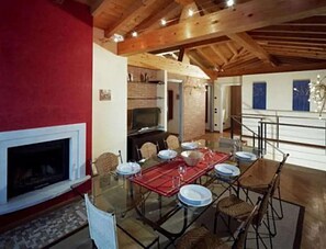 Comedor con mesa de vidrio, sillas y chimenea.