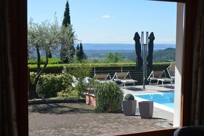 Zona junto a la piscina con sillones de descanso y vistas al paisaje.