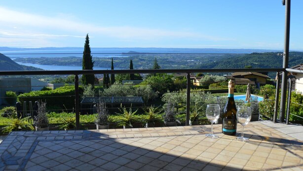 Una terraza con vistas a un valle, una botella de vino Zonin y dos copas.
