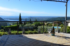 Une terrasse avec vue sur une vallée, une bouteille de vin Zonin et deux verres.