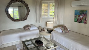 A room with two beds, a glass coffee table, a lamp, a mirror, a window with curtains, and a painting on the wall. - Very Spacious, Private, Open Plan Retreat. Pool And Stunning Views Of West Coast (Saint Peter)