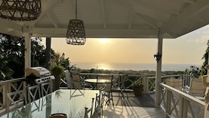An outdoor patio with a glass table, chairs, a grill, and a view of the ocean. - Very Spacious, Private, Open Plan Retreat. Pool And Stunning Views Of West Coast (Saint Peter)