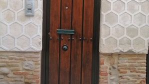 A wooden door with a metal handle and lock, set in a stone wall with a hexagonal pattern.