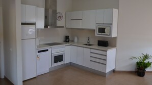 Een moderne keuken met witte kastjes, een magnetron, een koffiezetapparaat en een vaatwasser.