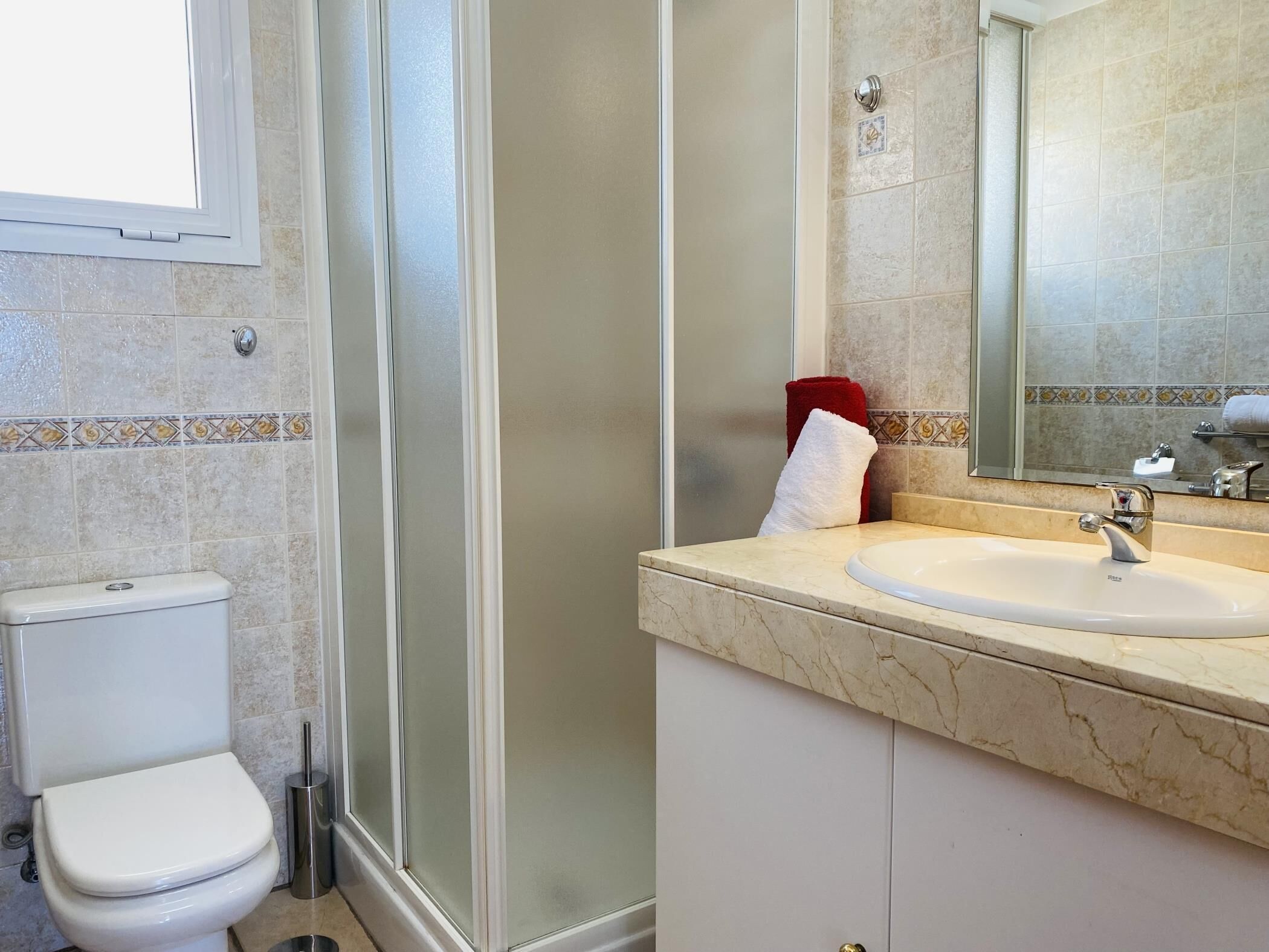 Une salle de bain avec des toilettes, un lavabo et une douche.