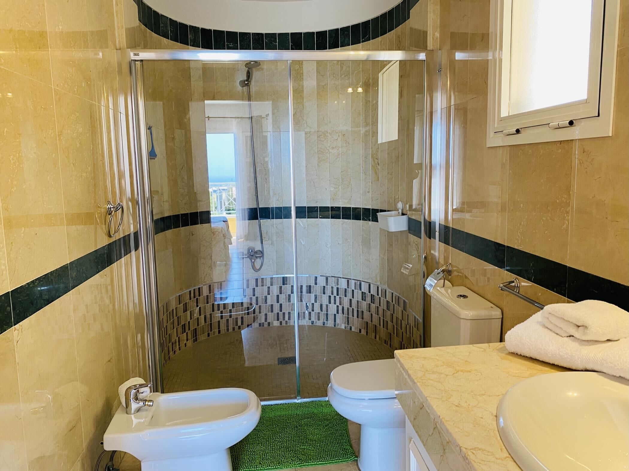 Une salle de bain moderne avec une douche à parois de verre, des toilettes, un bidet et un lavabo avec une serviette.