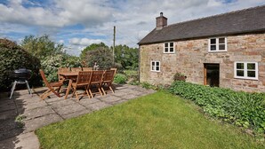 A stone house with a tiled roof, a paved patio, and a wooden table and chairs. - Croft Meadows Farm -  5 bedroom, dog friendly cottage in rural Staffordshire  (Leek)