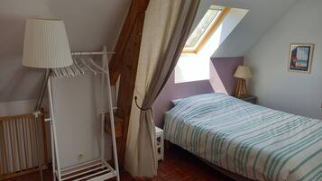 A bedroom with a bed, a hanging chair, a window with curtains, a lamp, and a poster on the wall.