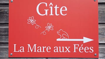 Een rood bord met witte tekst en een illustratie van een kikker, dat een richting aangeeft naar 'La Mare aux Fées'.