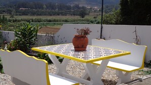 Ein helles Sitzgelegenheit im Freien mit Tisch aus Fliesen und einem Blumentopf.