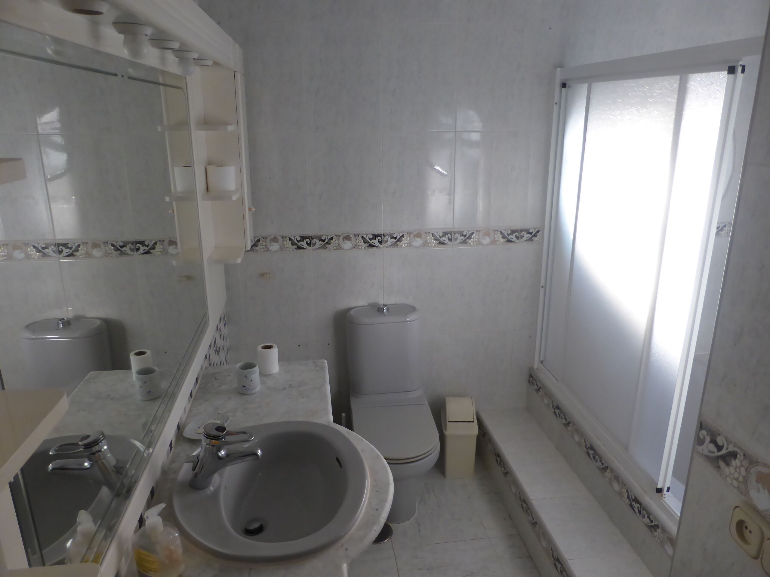 A bathroom with a sink, toilet, and mirror.