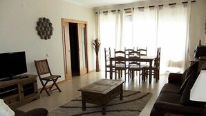 Un salon comprenant un téléviseur, une table basse, un canapé, une table à manger avec des chaises et un radiateur.
