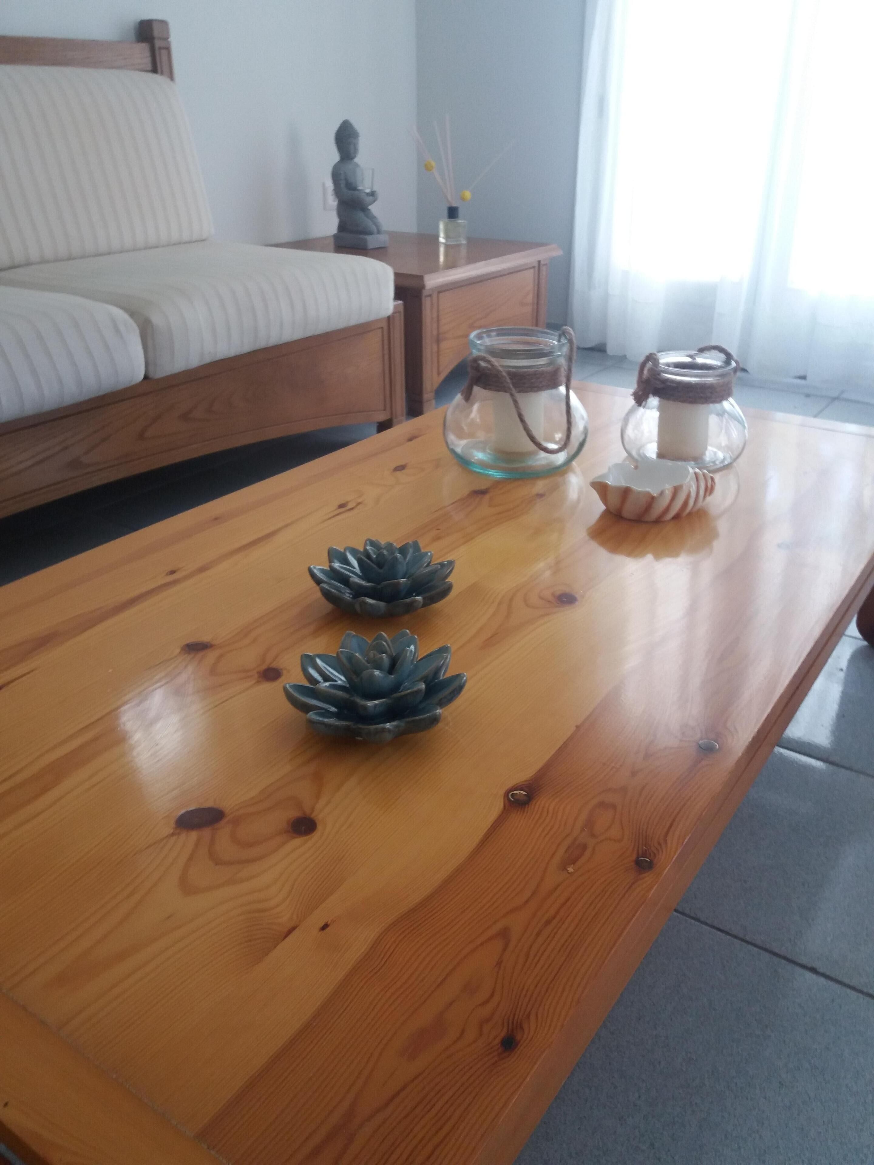 A wooden coffee table with two decorative succulents and two glass jars with candles.