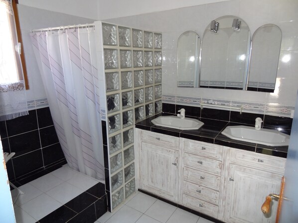 Un baño con dos lavamanos, una ducha y un espejo grande.