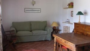 A room with a green sofa, wooden table, and a lamp.