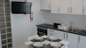 Ett modernt kök med vita skåp, en svart bänkskiva och ett matbord med plats för fyra personer.