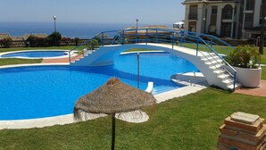 A pool with a blue and white design, a thatched umbrella, and a staircase leading to a building. - Excellent house facing the sea in urbanization with community pool (Almuñécar)