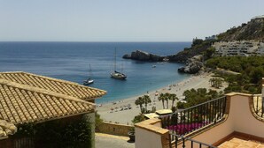 A coastal view with a beach, boats, and a rocky cliff. - Excellent house facing the sea in urbanization with community pool (Almuñécar)